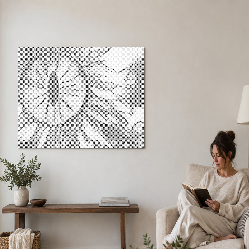 Dot-painting canvas “Sunflower Eye”, on a living-room wall with a person reading in an armchair nearby.