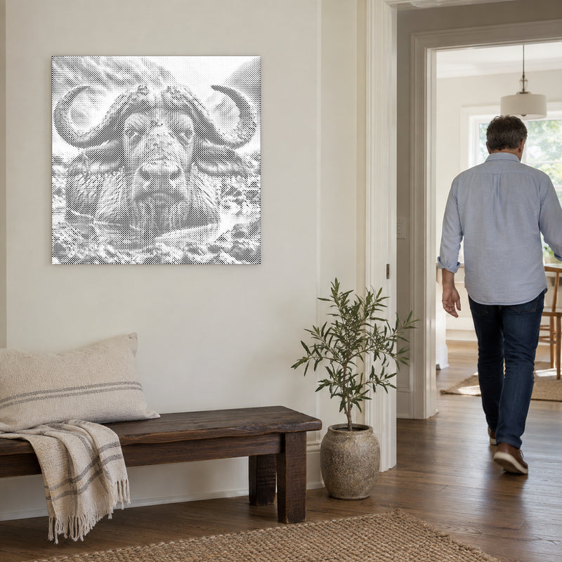 Dot-painting canvas “Water Buffalo”, on a light wall with a person walking through the doorway nearby.